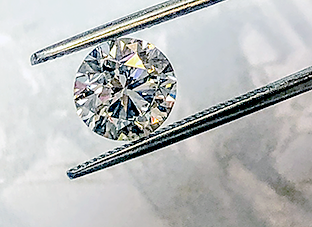 A 2 carat diamond being held up by tweezers