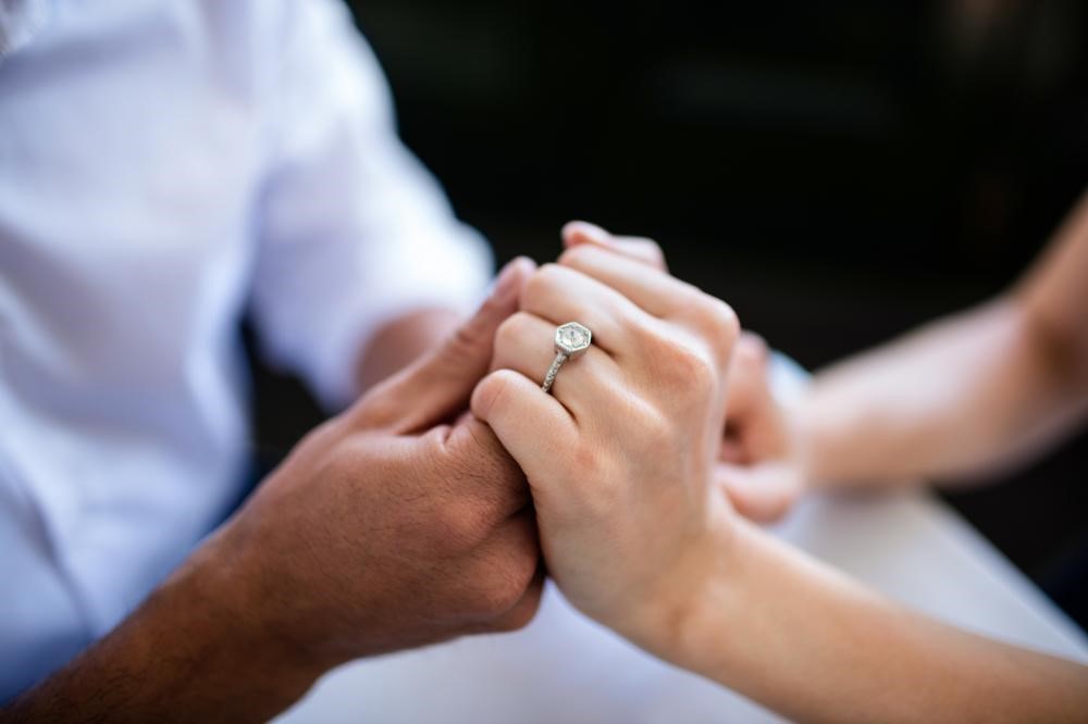 Groom and bride holding hands with ring showing on her finger