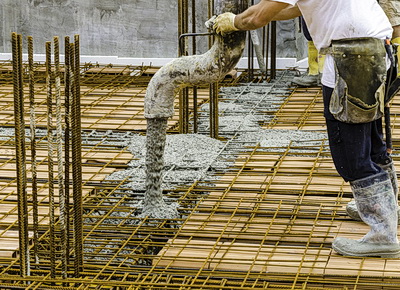Construction worker worket pours concrete into rebar frame