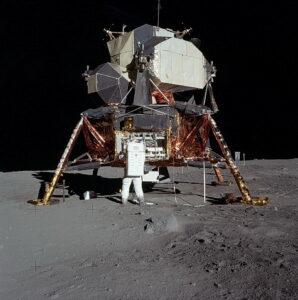 Buzz Aldrin removing the passive seismometer from a compartment in the SEQ bay of the Lunar Lander